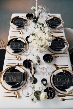 the table is set with black and white plates, gold rimmedware, and floral centerpieces