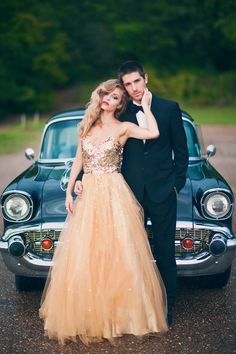 a man and woman in formal wear standing next to an old car