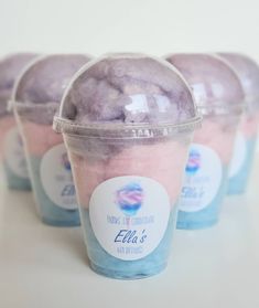 four ice creams in plastic cups with blue and pink toppings on the top