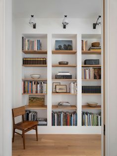 a chair sitting in front of a bookshelf filled with lots of books on top of wooden shelves