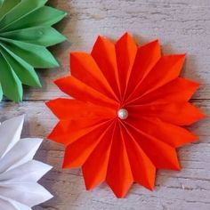 three colorful paper flowers sitting on top of a wooden table