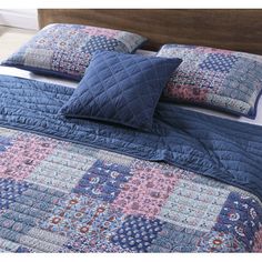 a bed with blue and pink quilted bedspread, pillows and pillow cases