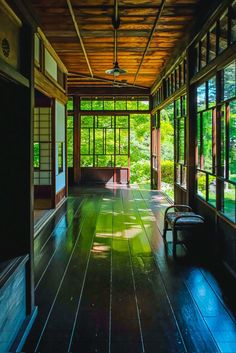 an empty room with lots of windows and wood flooring on the outside wall, in front of trees