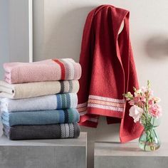 a stack of towels sitting on top of a table next to a vase with flowers