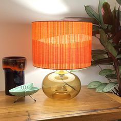 a lamp that is sitting on top of a table next to a potted plant