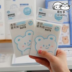 someone holding up two sticky notes in their hand, one with a teddy bear on it