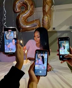 three people are holding up their cell phones to take pictures with the birthday candles in front of them