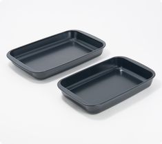 two black trays sitting next to each other on a white surface with one empty