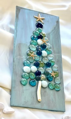 a christmas tree made out of marbles and starfish on top of a white sheet