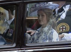 a woman sitting in the back seat of a car next to a man wearing a suit and tie