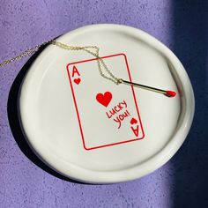 a white plate with a playing card on it and a matchstick in the middle