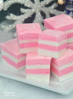 several pieces of pink and white cake sitting on a plate next to a christmas tree