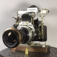 an old fashioned camera is sitting on top of a wooden stand with a metal object attached to it