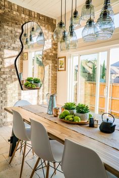 a dining room table that has some fruit on it and lights hanging from the ceiling