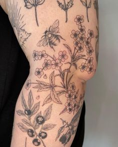 a woman's arm with tattoos on it, including flowers and leaves in black ink