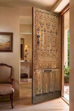 an ornate wooden door is open to the living room and dining area, while a chair sits in front of it