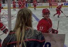 some girls are playing hockey on an ice rink and one girl is holding a sign