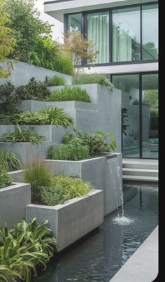 an outdoor garden with water and plants on the wall, along with concrete planters