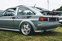 an image of a car that is parked in the grass with other cars behind it