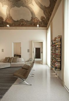 a large room with couches and books on the walls, along with a ceiling painted in gold