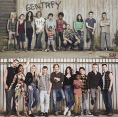 a group of people standing next to each other in front of a wall with graffiti on it