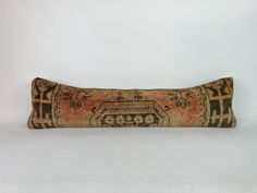 an old rug pillow is laying on the white floor with a black and orange pattern