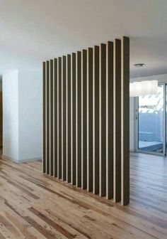 an empty room with wooden flooring and vertical slats on the wall behind it