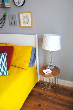 a bedroom with yellow bedding and pictures on the wall above it, along with a small side table