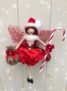 a red and white christmas elf doll hanging from a wall with candy canes in it's hand