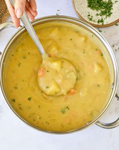 a person is spooning some food out of a pot filled with soup and bread