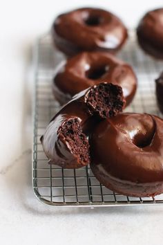 several chocolate donuts are on a cooling rack