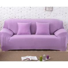 a purple couch sitting on top of a brown floor next to a white brick wall