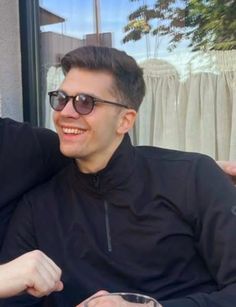 two men sitting next to each other at a table with drinks in front of them