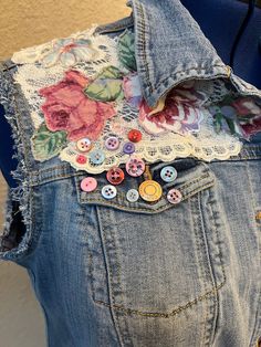 the back of a jean jacket with flowers and buttons on it's lapel