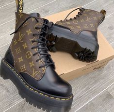 a pair of black and brown boots sitting on top of a cardboard box next to a wooden floor