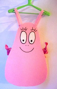 a pink object hanging from a green hanger with eyes and nose drawn on it