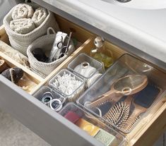 an organized drawer in a bathroom with soaps, hair brushes and other items inside