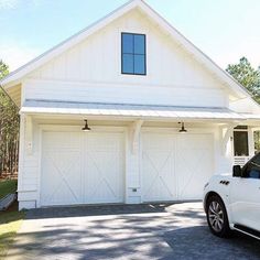 a white car is parked in front of a house with two garages on each side