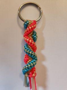 a red, blue and green beaded keychain hanging from a metal hook