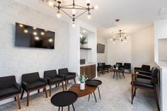 a waiting room with chairs, tables and a flat screen tv mounted on the wall