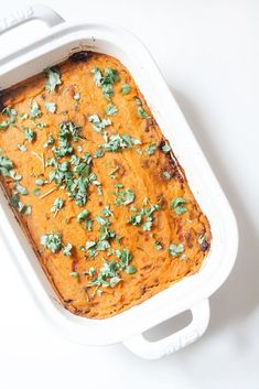 a casserole dish filled with sweet potatoes and garnished with parsley