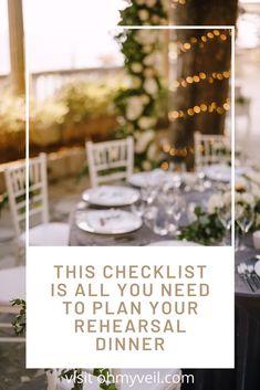 a table set up for a formal dinner with white chairs and greenery in the background