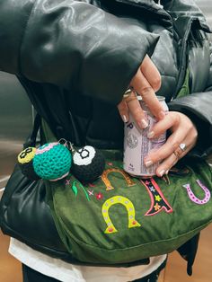 a woman is holding a purse with an owl design on it and two small pom poms