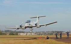 an airplane is taking off from the runway with people around it and in the background