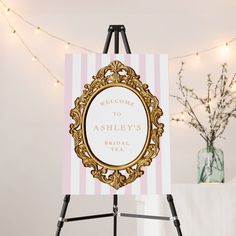 a welcome sign is on an easel next to a vase with flowers in it