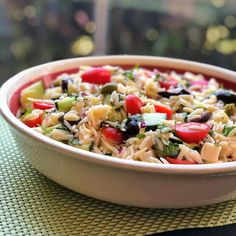 a white bowl filled with rice and veggies on top of a green table cloth