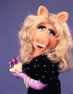 the miss piggy doll is dressed in black and purple with pearls on her head