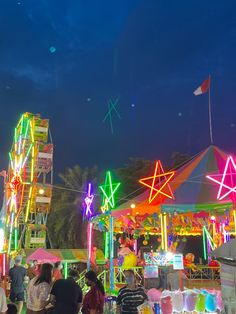 an amusement park at night with people standing around