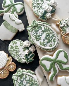 decorated cookies with green and white designs on top of a black tablecloth next to other decorations