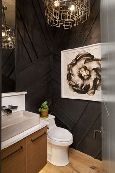 a white toilet sitting next to a bathroom sink under a light hanging from a chandelier